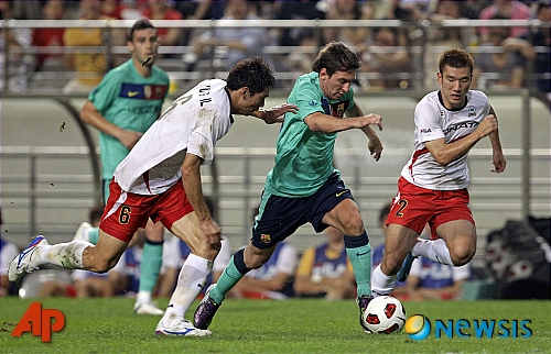 Spain's soccer club FC Barcelona's Lionel Messi of Argentina, center, fights for the ball with South Korea's K-League All Star team Kim Hyung-il, left, and Choi Hyo-jin during their friendly match at Seoul World Cup Soccer Stadium in Seoul, South Korea, Wednesday, Aug. 4, 2010. (AP Photo/ Lee Jin-man)