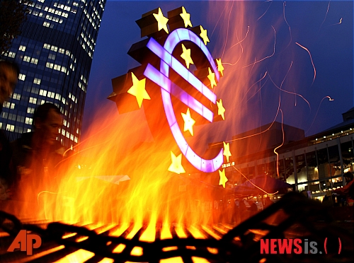 【프랑크푸르트=AP/뉴시스】독일 프랑크푸르트에 있는 유럽중앙은행(ECB) 본부 앞의 유로화를 상징하는 조각물 인근에서 '프랑크푸르트를 점령하라' 시위대가 붙인 불이 활활 타오르고 있다. 유럽 증시는 이날 ECB의 예기치 않은 기준금리 인하와 그리스의 국민투표 철회 소식에 힘입어 큰 폭으로 뛰어올랐다.