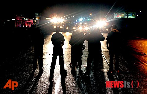 【퍼거슨=AP/뉴시스】16일(현지시간) 미국 미주리주 퍼거슨시 주민들이 경찰관의 총격으로 사망한 흑인 청년 마이클 브라운(18)을 추모하는 시위를 벌이고 있다. 사진은 시위대가 경찰관들과 대치하고 있는 모습. 2014.08.17