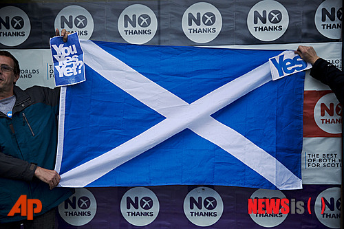 【에든버러=AP/뉴시스】15일(현지시간) 스코틀랜드 에든버러에서 분리독립에 찬성하는 2명의 활동가들이 독립에 반대하는 운동 진영인 '베터 투게더(Better Together)'의 사무실 밖에서 스코틀랜드기를 흔들고 있다. 스코틀랜드 분리독립 주민투표가 통과되면 스코틀랜드는 영국에서 떨어질 뿐만 아니라 유럽연합(EU)과 미국이 주도하는 북대서양조약기구(NATO·나토) 가입에 어려움이 따를 수도 있다. 2014.09.16