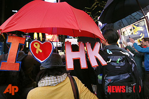【뉴욕=AP/뉴시스】1일(현지시간) 미국 뉴욕 타임스스퀘어에서 한 여성이 '아이 러브 홍콩'이라는 알파벳이 달린 빨간색 우산을 들고 가고 있다. 이날 미 전역에서 홍콩 민주화 시위를 지지하는 동조 시위가 열렸다. 최근 홍콩 시위대가 경찰이 쏜 최루가스를 막기 위해 우산을 펼쳐든 사진이 확산되면서 이들의 민주화 시위는 '우산혁명'이라는 별명을 얻게 됐다. 2014.10.02 