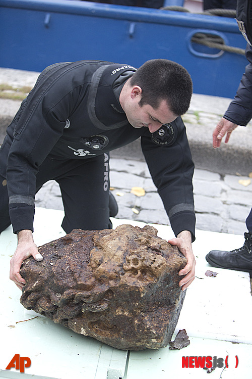 【파리=AP/뉴시스】프랑스 수상경찰이 20일(현지시간) 파리 세느강 퐁네프다리 밑에서 발굴한 석상을 세느강 둔치에 놓고 살펴보고 있다. 프랑스 당국은 이날 세느강 강바닥에서 수 세기 전 제작됐을 것으로 추정되는 의문의 이 석상을 발굴했다. 현지 수상경찰이 이날 밤 파리에서 가장 오래된 퐁네프 다리 밑 세느강 강바닥에서 가로 60cm, 세로 90㎝의 곱슬머리 인물상을 끌어올렸다. 2014.11.22