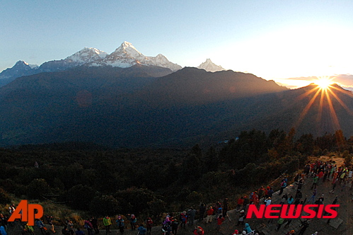 In this Friday, Oct. 24, 2014 photo, the sun rises above the Annapurna Range in central Nepal as viewed from Poon Hill, above the village of Ghorepani. Poon Hill, the highest point of the six-day, 65-kilometer (40-mile) loop through the villages of Ghandruk and Ghorepan can be crowded with other trekkers at sunrise during peak trekking season. (AP Photo/Malcolm Foster)