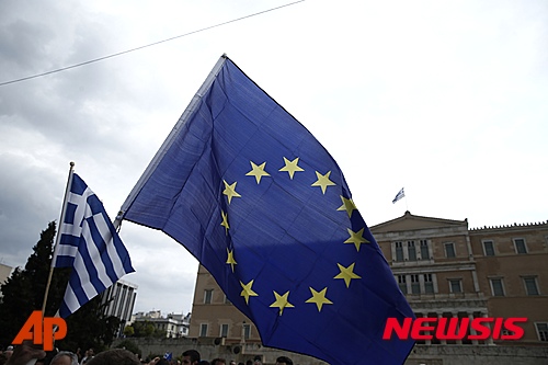 【아테네=AP/뉴시스】30일(현지시간) 그리스 아테네 신타그마 광장 데모 시위에서 다가오는 국민투표의 “찬성 투표” 지지자가 유럽연합 국기와 그리스 국기를 동시에 들고 있다. 그리스는 선진국가 중 국제통화기금(IMF) 부채를 상환하지 못한 첫번째 나라가 되었다. 그리스는 현재 사실상 디폴트 위기에 빠져 있으며 전국적으로 자본 통제가 이뤄지고 있다. 2015.07.01 