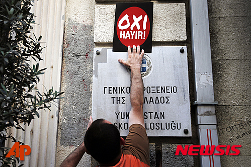 【이스탄불=AP/뉴시스】시위자가 터키 이스탄불에서 열린 그리스 국민과의 연대를 보여주는 집회에서 터키 주재 그리스 영사관에 그리스 국민투표와 관련해 '반대'를 뜻하는 그리스어와 터키어가 쓰여 있는 스티커를 붙이고 있다. 좌파 시위대는 이날 그리스 구제금융안 국민투표를 앞두고 반대를 지지하는 집회를 열었다. 2015.07.05 