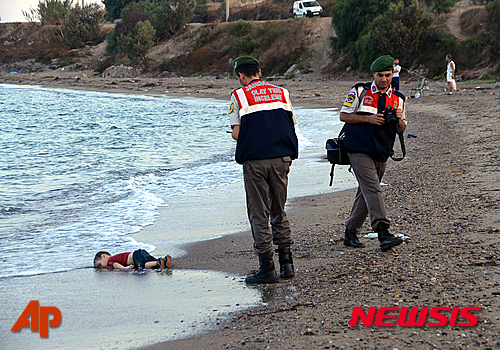 RETRANSMISSION TO REMOVE REFERENCE OF BID TO MOVE TO CANADA -Paramilitary police officers investigate the scene before carrying the lifeless body of Aylan Kurdi, 3, after a number of migrants died and a smaller number were reported missing after boats carrying them to the Greek island of Kos capsized, near the Turkish resort of Bodrum early Wednesday, Sept. 2, 2015. The tides also washed up the bodies of Rehan and Galip on Turkey's Bodrum peninsula Wednesday, Abdullah survived the tragedy. (AP Photo/DHA) TURKEY OUT ONLINE OUT