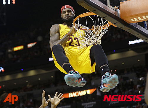 FILE - In this Dec. 25, 2014, file photo, Cleveland Cavaliers forward LeBron James (23) hangs onto the basket after a dunk during the second half of an NBA basketball game. More than any current player, LeBron James understands what it takes to reach the NBA Finals. The route, strewn with obstacles and doubts, has become a personal path. He knows the way. James has been to the league's showcase event five straight years and six times in the past nine. (AP Photo/Lynne Sladky, File)