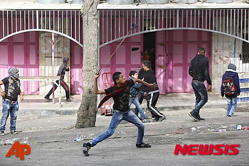 【헤브론=AP/뉴시스】4일(현지시간) 한 팔레스타인 청년이 요르단강 서안지구의 헤브론시에서 이스라엘 군인을 향해 돌멩이를 던지고 있다. 2015.11.5