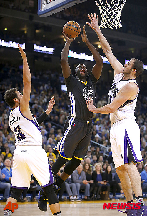Golden State Warriors forward Draymond Green (23) shoots between Sacramento Kings' Kosta Koufos, right, and Marco Belinelli (3) during the second half of an NBA basketball game Saturday, Nov. 28, 2015, in Oakland, Calif. The Warriors won 120-101. (AP Photo/Tony Avelar)