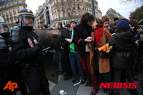 【파리=AP/뉴시스】제21차 유엔기후변화협약 당사국총회(COP21) 개막을 하루 앞둔 29일(현지시간) 프랑스 파리 레퓌블리크 광장에서 시위를 벌이는 동안 한 커플이 경찰 앞에서 키스를 하고 있다. 2015.11.30