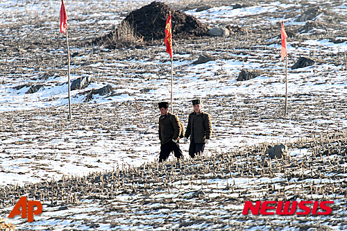 【단둥=AP/뉴시스】북한 삭주읍에서 7일 군인들이 눈내린 밭을 걸어가며 압록강 너머 단둥 쪽을 바라보고 있다. 2016.01.08 