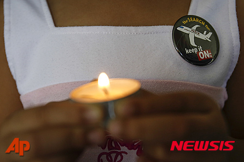 【쿠알라룸푸르=AP/뉴시스】말레이시아 쿠알라룸푸르 교회에서 8일 한 여성이 2년전 실종된 말레이시아항공 여객기 MH370편 승객들을 추모하는 촛불을 들고 있다. 가슴에서는 "수색을 계속하자"고 쓰여있는 배지를 달고 있다. 2016.03.08 