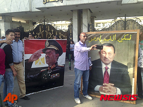 【카이로=AP/뉴시스】이집트 남성이 25일(현지기간) 카이로에서 호스니 무바라크 전 독재자 사진 앞에서 자신의 휴대전화로 사진을 찍고 있다 . 왼쪽 사진은 안와르 사다트 전 이집트 대통령이다. 2016.04.26 