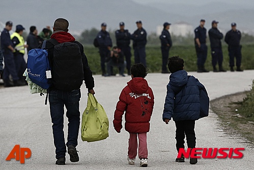 【이도메니=AP/뉴시스】그리스 이도메니 난민촌에서 24일(현지시간) 한 남성이 아이들과 함께 경찰들이 서있는 쪽으로 걸어가고 있다. 그리스 경찰은 이날부터 이도메니 난민촌 철거작업을 시작, 난민들을 정부 관할 수용시설로 이주시켰다. 2016.05.24  