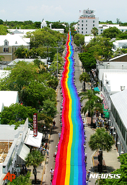 【키웨스트=AP/뉴시스】미국 플로리다주 키웨스트에서 15일(현지시간) 올랜도 게이클럽 총기난사 사건의 희생자를 추모하는 의미로 동성애를 상징하는 무지개 색 천들 들고 사람들이 행진하고 있다. 2016.06.16  
