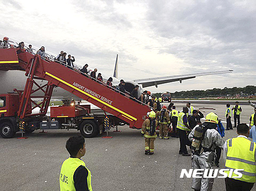 【 AP/뉴시스】싱가포르 창이 공항을 출발해 이탈리아 밀라노로 향하던 싱가포르 항공 SQ368편 보잉 777-300ER기가 27일 새벽 엔진 오일 경보에 따라 회항해 착륙하던 중 엔진에 화재가 발생했다. 사진은 AP가 입수한 것으로, 승객들이 질서있게 비행기에서 내리고 있다. 2016.06.27 