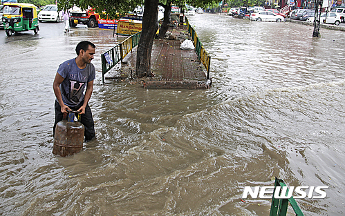 【뉴델리=AP/뉴시스】인도 남성이 30일(현지시간) 뉴델리에서 폭우로 물에 잠긴 도로에서 가스용기를 나르고 있다. 비하르주(州), 아삼주 등 북동부에는 이날 폭우로 홍수가 발생해 최소한 52명이 숨지고 수만 명의 수재민이 발생했다고 정부가 밝혔다. 2016.07.30