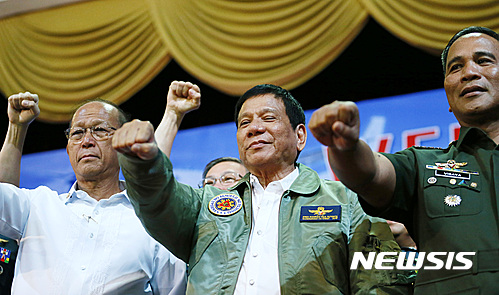 【파사이=AP/뉴시스】필리핀의 로드리고 두테르테 대통령(가운데)이 13일 공군 본부에서 국방장관 및 군 총사령관과 함께 주먹을 흔들며 결의을 다지고 있다. 2016. 9. 13.   