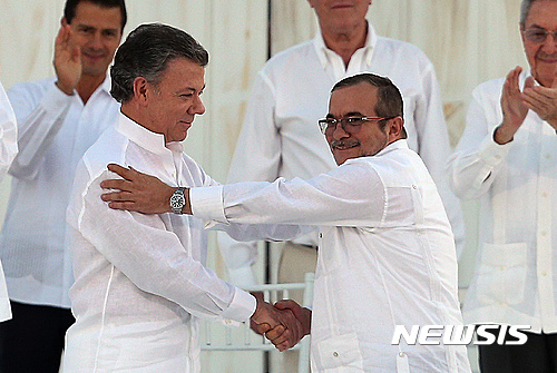 【카르타헤나=AP/뉴시스】후안 마누엘 산토스 콜롬비아 대통령(앞줄 왼쪽)과 콜롬비아무장혁명군(FARC) 최고지도자 로드리고 론도뇨(일명 티모첸코)가 26일(현지시간) 카르타헤나에서 평화협정에 서명한 후 악수하고 있다. 라울 카스트로 쿠바 국가평의회 의장(뒷줄 오른쪽),엔리케 페냐 멕시코 대통령(뒷줄 왼쪽) 등 국제사회 지도자들이 축하 박수를 치고 있다. 이날 행사 참석자들은 모두 평화를 상징하는 흰옷을 입었다. 2016.09.27 