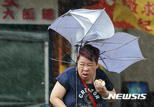 【타이베이=AP/뉴시스】제7호 태풍 메기가 27일 대만에 상륙하면서 한 여성이 타이베이에서 강풍에 우산을 쓰고 힘들게 뭔가를 먹고 있다. 태풍이 대만에 상륙하면서 휴교령 휴장, 항공편 결항 등 비상이 걸렸다 2016.09.27