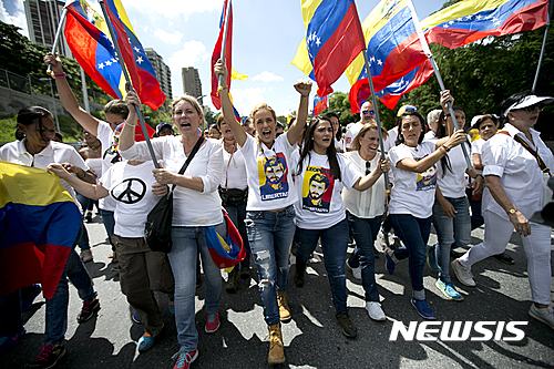 【카라카스=AP/뉴시스】투옥된 베네수엘라 야당 지도자 레오폴도 로페스의 부인 릴리언 틴토리(가운데)를 비롯한 구속인사 부인들이 22일(현지시간) 수도 카라카스에서 대통령소환 주민투표의 연기에 거세게 항의하며 시위대의 선두에서서 행진하고 있다. 야당은 선거 연기와 주민 서명운동 금지를 '쿠데타'로 규정하고 결전을 선언했다. 2016.10.23     