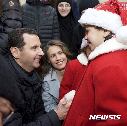 【 시리아대통령실·AP/뉴시스】시리아 내전이 6년동안 이어지고 있는 가운데 바샤르 알 아사드 대통령과 부인 아스마 여사는 25일(현지시간) 수도 다마스쿠스 북쪽 세드나야에 있는 수녀원을 찾아 산타클로스 옷을 입은 고아 어린이들과 크리스마스를 축하하고 있다. 사진은 시리아대통령실에서 페이스북을 통해 제공한 것이다. 2016.12.25  