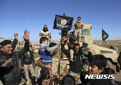 【모술=AP/뉴시스】이라크 군인들이 24일(현지시간) 모술 동부에서 이슬람 극단주의 무장단체 이슬람국가(IS)의 깃발을 들고 주민들과 해방을 축하하고 있다. 하이데르 알아바디 이라크 총리는 이날 주례 기자회견에서 모술 동부가 이슬람 극단주의 무장단체 이슬람국가(IS)로부터 완전 해방됐다고 밝혔다. 2017.01.25