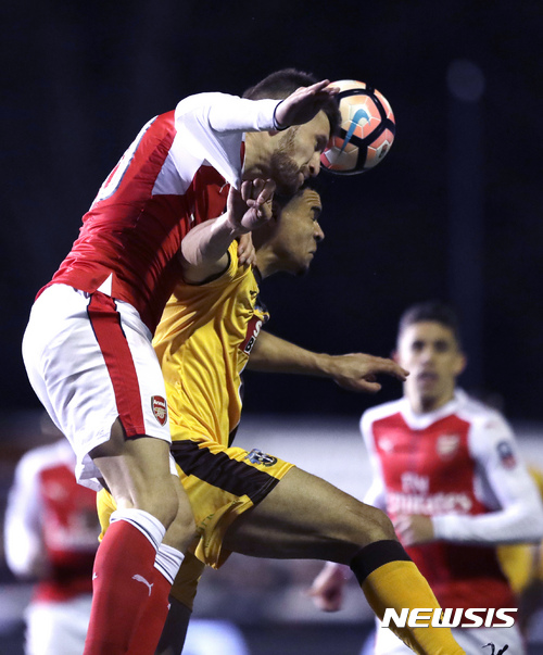 Arsenal's Shkodran Mustafi, left, heads the ball away from Sutton United's Maxime Biamou during their English FA Cup fifth round soccer match at Gander Green Lane stadium in London, Monday, Feb. 20, 2017. (AP Photo/Matt Dunham)