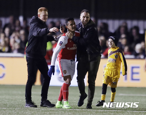 Spectators embrace Arsenal's Alexis Sanchez following the English FA Cup fifth round soccer match between Arsenal and Sutton United at Gander Green Lane stadium in London, Monday, Feb. 20, 2017. Arsenal defeated Sutton United 2-0. (AP Photo/Matt Dunham)