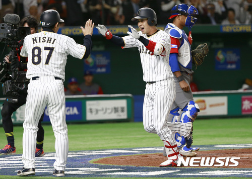 Japan's leadoff man Tetsuto Yamada, right, celebrates with coach Toshihisa Nishi after hitting a solo home-run off Cuba's starter Vladimir Banos during the first inning of their second round game at the World Baseball Classic at Tokyo Dome in Tokyo, Tuesday, March 14, 2017. (AP Photo/Shizuo Kambayashi)