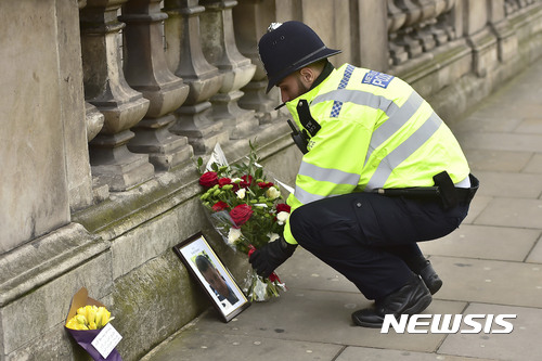 【런던=AP/뉴시스】23일(현지시간) 영국 런던의 국회의사당 밖에서 한 경찰관이 테러로 숨진 동료를 추모하기 위해 꽃을 내려놓고 있다. 전날 이 곳에서 차량 돌진·흉기 테러가 발생해 3명이 숨지고 40여 명이 다쳤다. 2017.3.23. 
