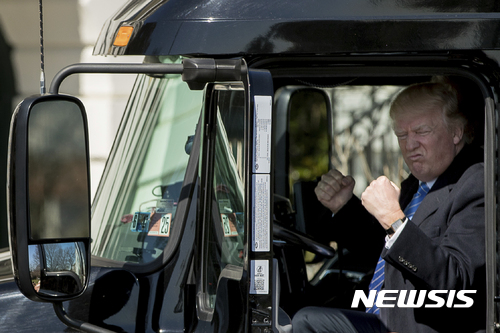 【워싱턴=AP/뉴시스】도널드 트럼프 미국 대통령이 23일(현지시간) 워싱턴 백악관 정원에서 트럭 운전자 및 업계 최고경영자(CEO)들을 지켜보는 가운데 바퀴 18개짜리 초대형 트레일러 운전석에 올라타 두 손을 불끈 쥐어보이고 있다. 2017.03.24  