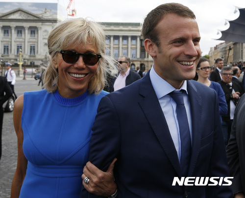 프랑스 중도 대선 후보 에마뉘엘 마크롱 전 경제장관이 14일(현지시간) 아내 브리짓 트로뉴와 파리에서 프랑스 혁명 기념 열병식 행사장에 도착하고 있다. <파리=AP/뉴시스>