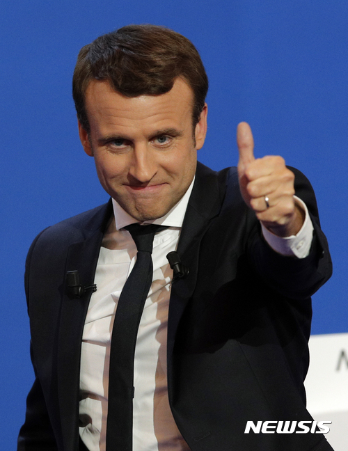 French centrist presidential candidate Emmanuel Macron thumbs up as he addresses his supporters at his election day headquarters in Paris , Sunday April 23, 2017. Macron and far-right populist Marine Le Pen advanced Sunday to a runoff in France's presidential election, remaking the country's political system and setting up a showdown over its participation in the European Union. (AP Photo/Christophe Ena)