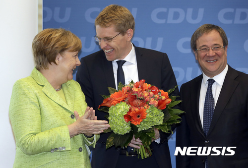 【베를린=AP/뉴시스】앙겔라 메르켈 독일 총리(왼쪽)가 8일(현지시간) 베를린에 있는 기독교민주당(CDU) 당사에서 열린 한 행사에서 다니엘 귄터 독일 슐레스비히홀슈타인 주의회 선거의 기독민주당 대표 후보에게 꽃다발을 주고 있다. 그는 이날 프랑스 대통령선거 결선에서 당선된 중도신당 ‘앙 마르슈’의 에마뉘엘 마크롱 후보에 대한 기대감을 표명했다. 2017.05.09 