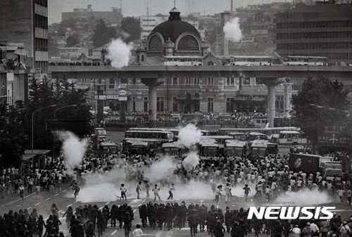 【서울=뉴시스】 1987년 6월 26일 서울역 앞 시위현장에서 달아나는 시위대 위로 발사된 최루탄이 터지고 있다. (사진=정태원 제공)(* 위 사진은 재배포, 재판매, DB 및 활용을 금지합니다.)photo@newsis.com
