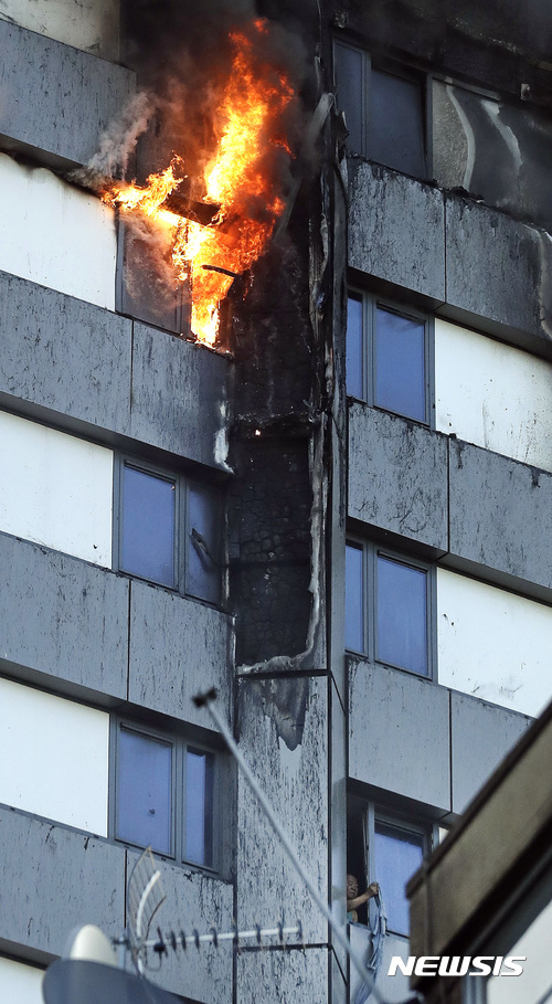 【런던=AP/뉴시스】 영국 런던 고층아파트에서 14일(현지시간) 초대형 화재가 발생한 가운데 한 남성이 천을 흔들며 구조를 요청하고 있다. 2016.06.14  