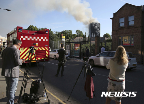 【런던=AP/뉴시스】 영국 런던에서 14일(현지시간) 취재진이 고층 아파트에서 발생한 화재로 연기가 치솟는 모습을 바라보고 있다. 2017.06.14 