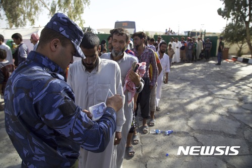 【모술(이라크) = AP/뉴시스】차미례 기자 = 이라크 모술 부근의 탈 아파르 검문소에서 이라크 경찰이 8월 26일 피난민들의 소지품과 신분증을 검사하고 있다. 8월 31일 이라크 총리는 이 일대의 완전 탈환을 선언한 이후 IS대원 가족들 1400여명이 이 곳 수용소에 수용된 것으로 알려졌다.  