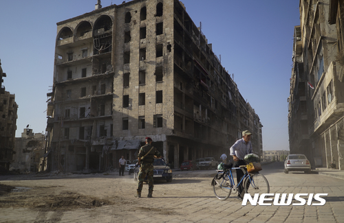 【알레포(시리아)=AP/뉴시스】시리아 알레포에서 12일(현지시간) 한 남성이 자전거를 끌고 지나가고 있다. 