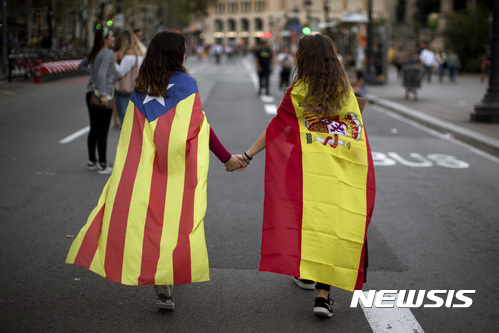 【바르셀로나=AP/뉴시스】지난 3일(현지시간) 스페인 바르셀로나에서 스페인 국기(오른쪽)와 카탈루냐 독립기 에스텔라다를 각각 몸에 두른 여학생들이 손을 잡고 거리를 걷고 있다. 2017.10.20.