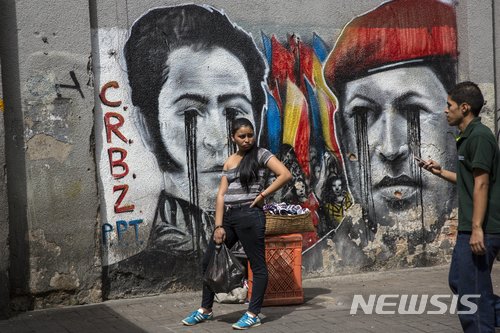【카라카스( 베네수엘라) = AP/뉴시스】 베네수엘라의 극심한 경제난과 국제적 고립속에서 수도 카라카스의 우고 차베스 전대통령(오른쪽)과 독립영웅 시몬 볼리바르의 초상화가 검은눈물을 흘리고 있다. 마두로 정부는 반부패 소탕전을 벌이면서 국영석유회사의 미국계 자회사 시트고의 임원 6명을 11월 21일( 현지시간) 체포했다.  