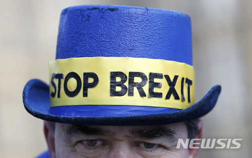 【런던=AP/뉴시스】영국 런던 웨스트민스터 국회의사당 앞에서 8일(현지시간) 한 남성이 '브렉시트 스톱'이라고 쓴 띠를 두른 모자를 쓰고 브렉시트 반대 시위를 벌이고 있다. 이날 테리사 메이 영국 총리와 장 클로드 융커 유럽연합 집행위원장은 브렉시트 1단계 협상을 마무리했다고 발표했다. 2017.12.08