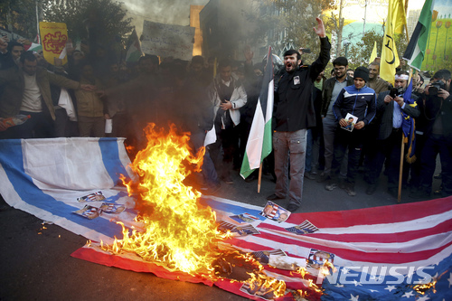 【테헤란(이란) = AP/뉴시스】 이란 시위대가 도널드 트럼프 대통령이 지난 해 12월 예루살렘을 이스라엘의 수도라고 선언한 뒤에 성조기와 이스라엘기를 거리에서  태우며 항의 집회를 열고 있다.   