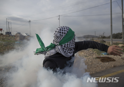 【비르제이트=AP/뉴시스】19일(현지시간) 팔레스타인 자치구역 서안지구에서 반미 시위에 참석한 한 남성이 이스라엘군을 향해 가스통을 던지고 있다. 2017.12.20. 