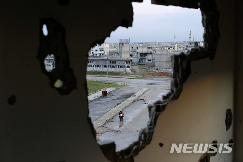 【홈스=AP/뉴시스】16일(현지시간) 시리아 홈스에서 공습 때문에 건물 벽에 난 구멍 사이로 시내 전경이 보이고 있다. 2018.1.17. 