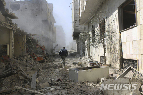 【구타 ( 시리아) = AP/뉴시스】 22일 시리아 정부군의 폭격과 포격으로 폐허가 된 동구타 지역에서 한 남성이 건물 사이로 달려가고 있다.  