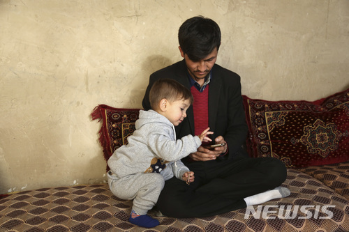 【카불=AP/뉴시스】아사둘라 포야가 지난 15일(현지시간) 아프가니스탄 카불에 있는 자신의 집에서 생후 1년 6개월된 3째 아들 도널드 트럼프와 휴대폰에 담긴 트럼프 미국 대통령의 사진을 보고 있다. 2018.03.16