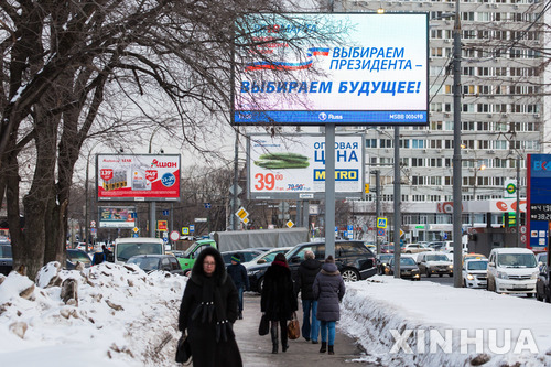 【모스크바 = 신화/뉴시스】 3월 18일 대통령 선거 투표가 실시된다는 모스크바 시내의 대형광고판 아래로 16일 보행자들이 지나가고 있다.  
