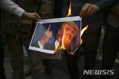 【테헤란=AP/뉴시스】9일(현지시간) 이란 수도 테헤란에서 시위대가 도널드 트럼프 미국 행정부의 이란 핵협정 탈퇴에 항의하며 트럼프의 사진을 태우고 있다. 2018.5.10.